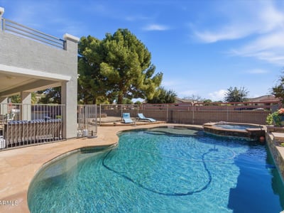 Sparkling backyard pool with spa, stone decking, and lounge space surrounded by mature trees for added privacy and shade.