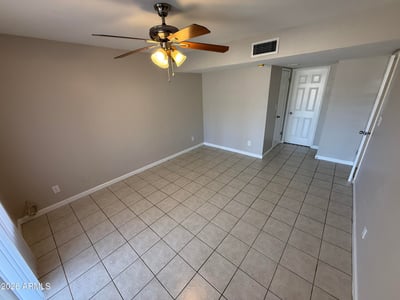 Light-filled bedroom with tile floors and large window providing exterior views. The space offers a bright environment ideal for relaxation.