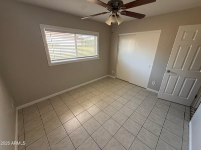Light-filled bedroom featuring tile flooring, neutral walls, and ceiling fan lighting. The open layout makes the space perfect for guests, family members, or a home office.