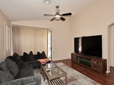 Spacious living area with ceiling fan, wood-look floors, and patio access. Perfect for everyday living and entertaining in this Phoenix property.