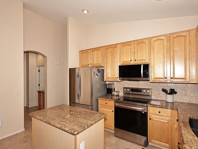 Kitchen with granite island, stainless appliances, and warm wood cabinetry. This Phoenix home provides functional prep space and a welcoming cooking area.