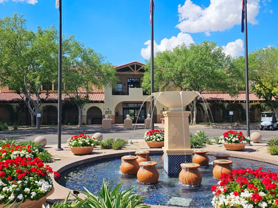 Clubhouse and fountain area surrounded by lush landscaping and mature trees. This Phoenix golf community offers a resort-style atmosphere and amenities.