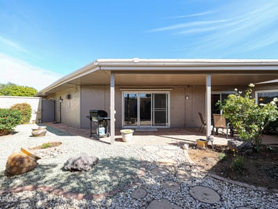 Private backyard with covered patio, desert landscaping, and outdoor seating areas ideal for relaxing or entertaining in Sun City.
