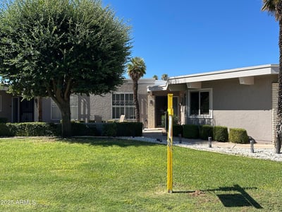 Well-maintained Sun City exterior with vibrant grass, mature landscaping, and a peaceful front approach that enhances the home s curb appeal and overall charm.