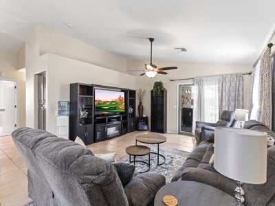 Comfortable family room with neutral finishes, ceiling fan, and open flow to kitchen and dining areas for easy living.