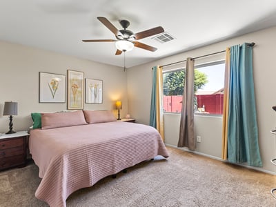 Spacious primary bedroom featuring large window, ceiling fan, and plush carpet creating a relaxing private retreat.