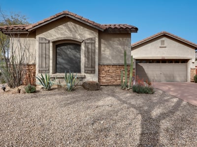 Attractive Phoenix home with desert landscaping, stucco exterior, and stone details, offering low-maintenance curb appeal and a welcoming entrance.
