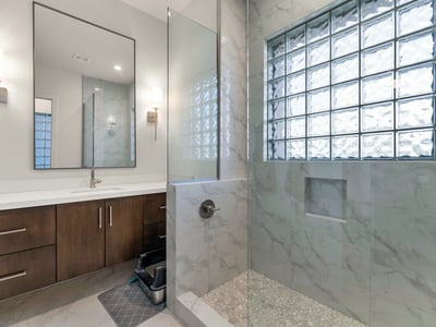 Well-appointed bathroom with dual sinks, updated cabinetry, and glass block accents for natural light in this Phoenix home.