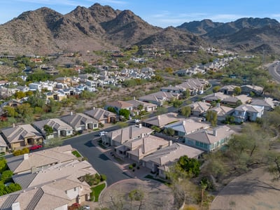 Wide aerial view of a Phoenix neighborhood set against picturesque mountains, highlighting location, nearby homes, and desert surroundings.