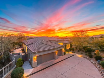 Beautifully maintained Scottsdale home with modern architecture, spacious driveway, and warm exterior lighting set against a vibrant sunset backdrop.