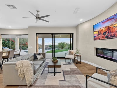 Open-concept living room with sleek fireplace, wood floors, and sliding doors leading to the backyard, showcasing Scottsdale indoor-outdoor design.