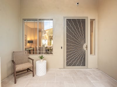 Covered Scottsdale front patio with seating area and decorative security door, offering charm and privacy.