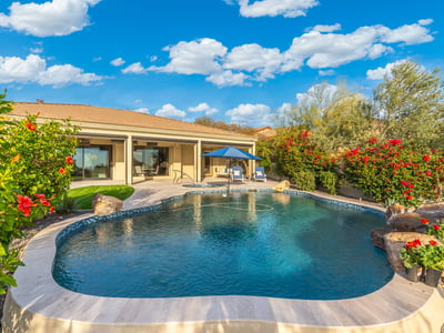 Scottsdale outdoor living area with pool, covered patio, and landscaped yard, offering comfortable indoor-outdoor flow.