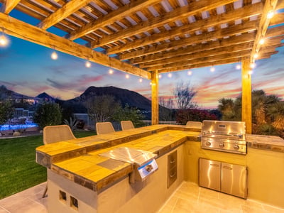 Scottsdale outdoor kitchen with built-in grill, seating area, and scenic mountain backdrop, designed for hosting gatherings.
