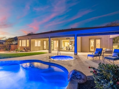 Scottsdale backyard featuring glowing spa, poolside seating, and covered patio, ideal for evening relaxation and entertaining.