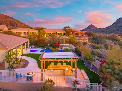 Scottsdale backyard featuring a pergola-covered outdoor kitchen with built-in grill and seating, perfect for entertaining with views of the pool and desert.