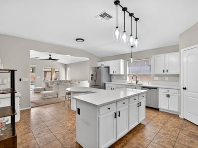 Spacious kitchen with large island, white cabinetry, and ample prep space. Open layout flows into living areas, making it ideal for gatherings in this Casa Grande property.