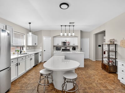 Functional kitchen with breakfast bar, white cabinets, and modern appliances. Seamless connection to living areas enhances flow in this Casa Grande home.