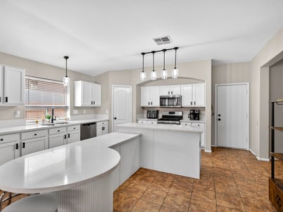 Bright open kitchen with large island, white cabinetry, and modern lighting. Perfect for entertaining and daily living in this Casa Grande home.