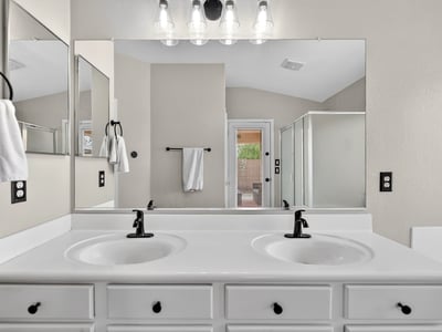 Spacious primary bathroom with dual vanities and modern fixtures. Functional layout enhances everyday convenience in Casa Grande.