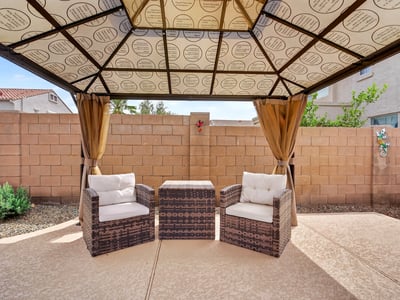 Backyard pergola with cozy seating creates a peaceful outdoor retreat. Perfect for relaxing near the pool in this Casa Grande home.