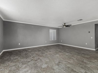 Spacious living area with modern flooring and ceiling fan. This Sun City home features an open floor plan perfect for relaxing or entertaining.