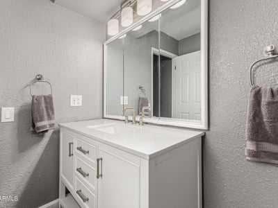 Well-lit vanity area with updated cabinetry and modern mirror. This Sun City home features upgraded bathrooms and functional design.