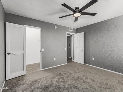 Spacious bedroom with neutral tones, ceiling fan, and convenient closet access. This Sun City home provides functional design and modern updates.