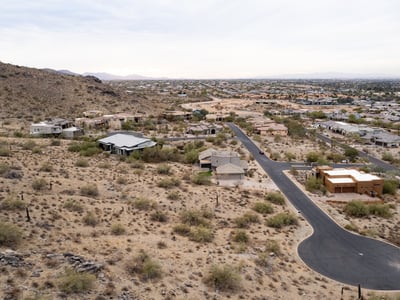 Exceptional aerial perspective showcasing the property s elevated setting among scenic desert terrain and luxury homes. Build your dream residence surrounded by breathtaking Phoenix mountain views.