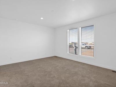 Comfortable primary suite offering generous dimensions, soft carpeting, and large windows that welcome natural light. A relaxing space designed for rest while enjoying peaceful desert surroundings.