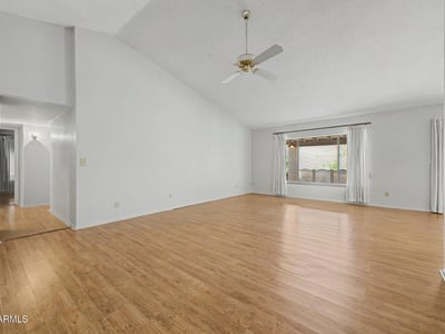 Vaulted ceilings and expansive living space define this bright great room. Wood-look flooring and natural light create an inviting setting perfect for entertaining guests or enjoying quiet evenings at home.