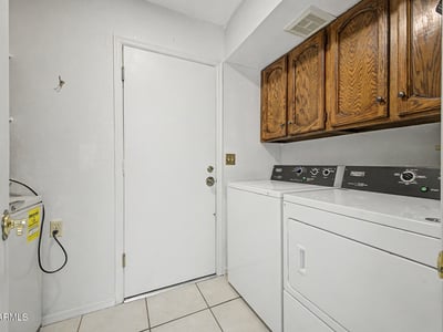 Complete with upper storage cabinets and included laundry appliances, this dedicated laundry room offers efficiency and convenience. The practical layout helps maximize organization and household functionality.