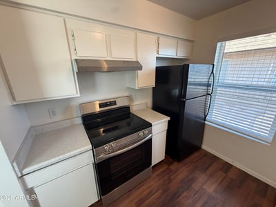 Kitchen highlights include updated black appliances, bright cabinetry, and easy-care countertops. The practical layout offers excellent workspace and storage for comfortable apartment living.