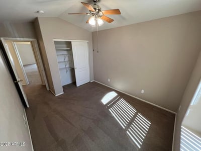 Spacious bedroom featuring a large closet, soft neutral tones, and ceiling fan. This versatile room offers flexibility for sleeping quarters, a hobby room, or a dedicated office space.