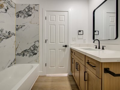 Elegant marble-look tile, a beautifully remodeled tub and shower, quartz countertops, and custom cabinetry combine to create a stylish, move-in-ready bathroom.
