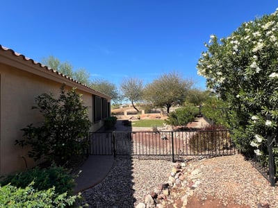 Beautiful side yard featuring flowering shrubs, decorative rock landscaping, gated access, and paver walkways that enhance both privacy and the home's low-maintenance outdoor design.