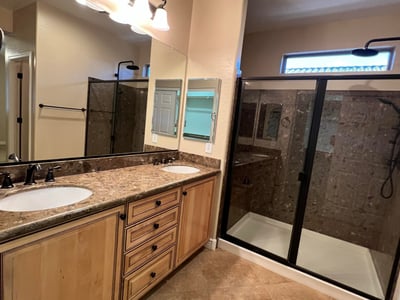 Beautiful primary bath offering dual vanities, abundant cabinetry, upgraded countertops, modern fixtures, and a spacious tiled walk-in shower. A relaxing retreat designed with both comfort and functionality in mind.