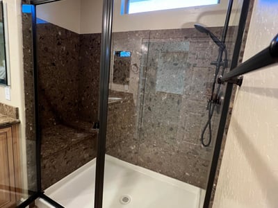 Luxurious walk-in shower with stylish tile surrounds, built-in bench seating, black framed glass enclosure, and upgraded shower fixtures creating a sophisticated spa-like experience.