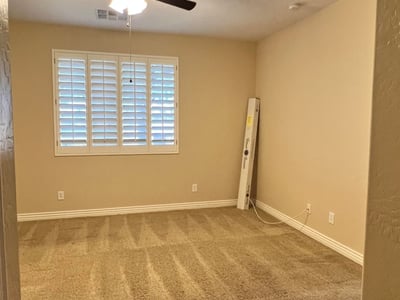 Inviting secondary bedroom featuring soft carpeting, plantation shutters, ceiling fan, and abundant natural light. Ideal as a guest suite, hobby room, or private office space.