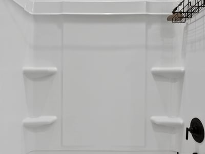 This updated bathroom includes a spacious tub and shower combination with contemporary matte black fixtures, built-in storage shelves, and low-maintenance finishes.
