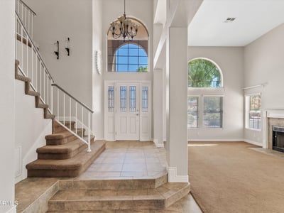 From the grand front entrance, enjoy views into the expansive living space featuring soaring ceilings, oversized windows, and abundant natural light. The open design enhances both comfort and entertaining.