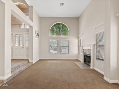 High ceilings, large arched windows, and a charming fireplace make this formal living room bright and welcoming. The spacious layout is ideal for gathering with family or entertaining guests.