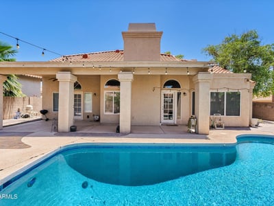 This covered patio overlooks the inviting swimming pool and landscaped backyard, offering comfortable outdoor living with plenty of space for entertaining and relaxing.