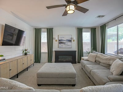 Inviting family room featuring a cozy fireplace, elegant accent wall, large windows, and an open layout. A perfect space to gather, unwind, and enjoy everyday comfort in this Waddell home.