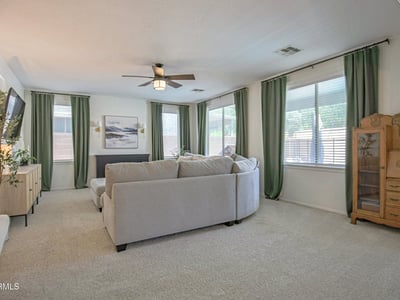 Bright family room filled with natural light from oversized windows, offering generous space for comfortable seating and effortless connection to the rest of this beautifully maintained Waddell home.