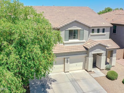 Front aerial image showcasing the home's attractive curb appeal, mature landscaping, three-car garage, and inviting exterior within a desirable Waddell neighborhood.