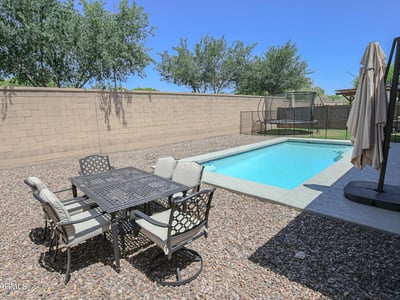Outdoor dining space positioned beside the sparkling swimming pool, creating the perfect setting for entertaining and enjoying Arizona's outdoor lifestyle. A wonderful backyard feature in this Waddell home.