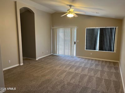 This oversized primary bedroom offers plush carpeting, a ceiling fan, abundant natural light, and generous space for a sitting area, creating a comfortable private retreat.