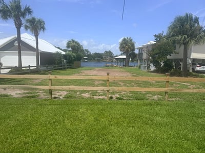 Scenic waterfront lot with potential for building, surrounded by palm trees and nearby waterfront homes.