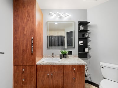 Modern bathroom featuring wooden cabinetry, a sleek countertop, and ample storage for everyday essentials.